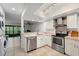 Modern kitchen with stainless steel appliances and light-colored cabinetry, flowing into living area at 3003 Quail Holw # 10, Sarasota, FL 34235