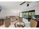 Spacious living room with comfortable seating and access to a screened lanai overlooking lush greenery at 3003 Quail Holw # 10, Sarasota, FL 34235