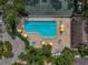 A top-down view of the pool with umbrellas and nearby tennis courts, showing the variety of amenities at 3003 Quail Holw # 10, Sarasota, FL 34235