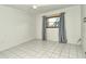 A simple bedroom with a window and grey curtains shows the empty space available at 3985 Maceachen Blvd # 224, Sarasota, FL 34233