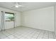 A simple bedroom with a window and white tile floors shows the empty space available at 3985 Maceachen Blvd # 224, Sarasota, FL 34233
