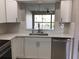 Modern kitchen featuring white cabinets, stainless steel dishwasher, and pass-through to the living area at 5178 Lake Village Drive # 86, Sarasota, FL 34235