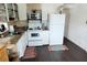 Well-lit kitchen with white appliances, open shelving, and dark wood-look flooring at 5233 Kenwood Ave, Sarasota, FL 34234