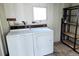 View of the laundry room, featuring a white washer and dryer, shelving, and a small window at 5233 Kenwood Ave, Sarasota, FL 34234