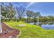 A lush backyard with a pond, green grass, mature trees, and attractive landscaping at 7005 Goldrush Ln, Bradenton, FL 34201