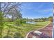 A peaceful backyard with a serene pond, lush green grass, mature trees, and pretty landscaping at 7005 Goldrush Ln, Bradenton, FL 34201