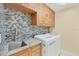This laundry room features stylish backsplash, wood cabinets, granite counters, and a new washer/dryer at 7005 Goldrush Ln, Bradenton, FL 34201