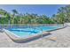 Community swimming pool with blue water, lounge chairs and umbrellas, surrounded by green trees at 7005 Goldrush Ln, Bradenton, FL 34201