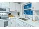 Kitchen featuring quartz countertops, stainless steel sink, and white cabinetry at 925 Beach Rd # 408, Sarasota, FL 34242