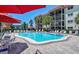 Bright community pool surrounded by patio, umbrellas, and tall palm trees at 925 Beach Rd # 408, Sarasota, FL 34242
