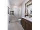 Modern bathroom features a frameless glass shower, a dark vanity, and a large mirror reflecting natural light at 1166 Blue Shell Loop, Sarasota, FL 34240