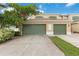 Townhouse with two-car garage, green doors, and lush landscaping framing the driveway and facade at 2303 28Th E Ave, Palmetto, FL 34221