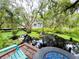 Tranquil backyard featuring a pond with a fountain, surrounded by mature trees and lush vegetation at 25640 State Road 70 E, Myakka City, FL 34251