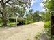 Long gravel driveway leading to a covered parking area shaded by mature trees, enhancing the property's curb appeal at 25640 State Road 70 E, Myakka City, FL 34251