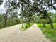 Long gravel driveway leading to the house, surrounded by mature trees and natural landscape at 25640 State Road 70 E, Myakka City, FL 34251