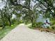 A long gravel driveway, lined with mature trees, leading to a charming home at 25640 State Road 70 E, Myakka City, FL 34251