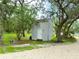 An exterior view of a gray shed accented by trees and landscaping for a serene and private feel at 25640 State Road 70 E, Myakka City, FL 34251