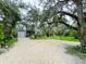 Two-story home with a gravel driveway, lush landscaping, attached garage, and neutral exterior at 25640 State Road 70 E, Myakka City, FL 34251