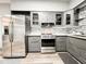 Well-lit kitchen boasts stainless steel appliances, granite countertops, gray cabinets, and a tile backsplash at 25640 State Road 70 E, Myakka City, FL 34251