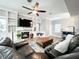 Spacious living room with built-in bookshelves, a stone fireplace, a ceiling fan, and a comfortable leather sofa at 25640 State Road 70 E, Myakka City, FL 34251