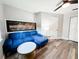 A cozy seating area with a blue sectional sofa, wood flooring, ceiling fan, and modern lighting at 25640 State Road 70 E, Myakka City, FL 34251