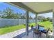 Covered patio shows table and chairs, as well as a view of the manicured backyard and perimeter fence at 3419 74Th Avenue E Cir, Sarasota, FL 34243