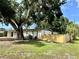 Exterior front view of the home features a big shade tree and new fence at 6031 11Th E St, Bradenton, FL 34203