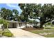 Exterior view of a charming single-story home with mature trees, landscaping, and a spacious driveway at 6031 11Th E St, Bradenton, FL 34203