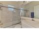 Tiled bathroom features a shower-over-tub combo with glass doors, and white vanity and cabinetry at 6644 Butlers Crest Dr, Bradenton, FL 34203