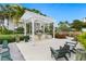 An outdoor community grilling area with a pergola, grill, seating, and lush landscaping at 7611 34Th W Ave # 301, Bradenton, FL 34209