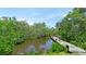 Scenic backyard canal view with private wooden dock surrounded by tropical vegetation and blue skies at 9403 9Th Nw Ave, Bradenton, FL 34209