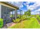 Spacious backyard featuring lush green grass, landscaping, and a screened in patio with pond view at 3025 Veneto Ct, Bradenton, FL 34211