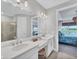 Bright bathroom with dual sink vanity, light sconces, and a view into the primary bedroom at 3025 Veneto Ct, Bradenton, FL 34211