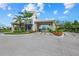 Elegant community entrance gate with stone pillars, a covered entryway, and manicured landscaping at 3025 Veneto Ct, Bradenton, FL 34211