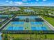 Aerial view of well-maintained blue and green tennis courts, part of a vibrant community with lake and surrounding greenery at 3025 Veneto Ct, Bradenton, FL 34211