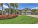 Beautiful home with lush landscaping, featuring vibrant red flowers and palm trees in the front yard at 11200 Whimbrel Ln, Sarasota, FL 34238