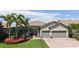 A charming home with a paver driveway, green lawn, and vibrant red flowers nestled around palm trees at 11200 Whimbrel Ln, Sarasota, FL 34238