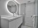 Stylish bathroom showcasing a round mirror with lighting, a sleek vanity, and a glass-enclosed shower at 1150 Tarpon Center Dr # 1-C 103, Venice, FL 34285