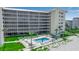 Beachfront condo building featuring a pool, lush landscaping, and screened balconies for enjoying ocean breezes at 1150 Tarpon Center Dr # 1-C 103, Venice, FL 34285
