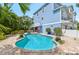 Backyard swimming pool surrounded by lush landscaping, brick pavers, and a colorful two-story home at 202 75Th St, Holmes Beach, FL 34217