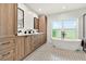 Modern bathroom with wood cabinets, freestanding tub, mosaic tile floor, and bright natural light at 2460 Hillview St, Sarasota, FL 34239