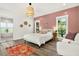 Stylish bedroom with a textured pink accent wall, woven pendant lighting, and light wood-look flooring at 2460 Hillview St, Sarasota, FL 34239