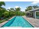 Backyard pool with lush landscaping, a covered patio, solar panels, and an outdoor seating area at 2460 Hillview St, Sarasota, FL 34239