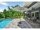Outdoor pool patio with an umbrella, tropical landscaping, a seating area, and access to the home at 2460 Hillview St, Sarasota, FL 34239