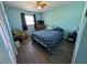 Cozy blue bedroom with wood-look floors, a ceiling fan, and a large window offering ample natural light at 3237 Pine Haven Dr, Clearwater, FL 33761