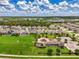 This aerial view shows a green space with a playground and nearby residential area under a blue sky at 3602 Secret Stroll Dr, Sarasota, FL 34240