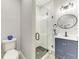 Modern bathroom features glass shower, blue vanity, hexagon tile floor, and round mirror at 4314 Des Plaines Dr, Sarasota, FL 34233
