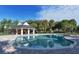 Resort-style swimming pool featuring a covered pavilion area, brick surround, and beautiful landscaping under a clear blue sky at 4649 72Nd E Ct, Bradenton, FL 34203