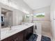 Bathroom featuring a double sink vanity, large mirrors, and a tiled shower with a glass partition at 4654 Claremont Park Dr, Bradenton, FL 34211