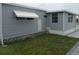 Home's exterior featuring neutral siding, awning, and well-kept lawn, blending comfort with outdoor charm at 5112 Glen Echo Ave, Sarasota, FL 34234
